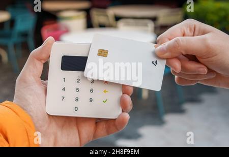 Crop unrecognizable female with plastic card making purchase for order on POS terminal in outdoors cafe in city Stock Photo