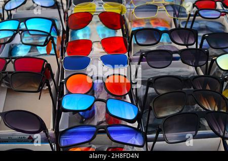 Sunglasses of different colors are arranged for sale Stock Photo