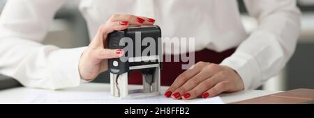 Businesswoman puts stamp on credit documents at work desk Stock Photo