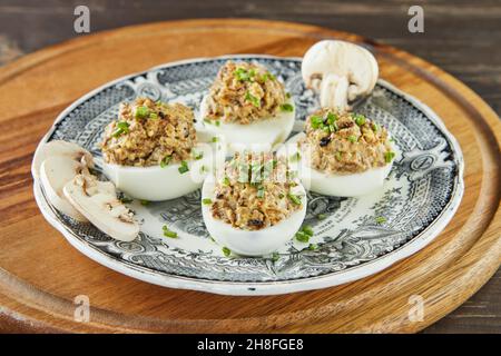 Stuffed Mimosa eggs with mushrooms in vintage plate. French gourmet cuisine Stock Photo