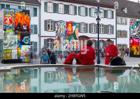 Basel, Switzerland - February 21. Carnival revellers in red costumes at the fountain on the cathedral square Stock Photo