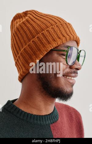 Vertical side view portrait of smiling African-American man wearing knit hat and sweater Stock Photo