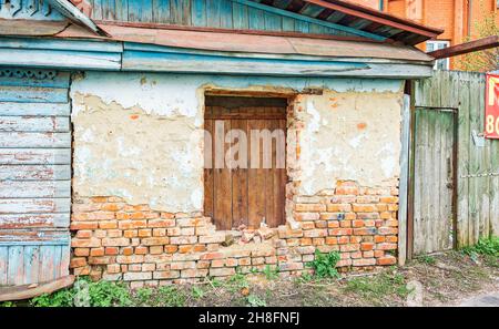 Old Russian brick house in dilapidated condition with boarded-up window Stock Photo