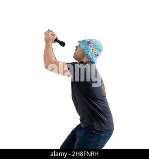 A funny mature man in a bright hat holds a microphone in his hands. Isolated on a white background. Stock Photo