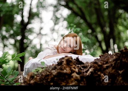 Rest, relaxation in the forest. A woman lies on a pillow on a tree surrounded by green foliage. Stock Photo