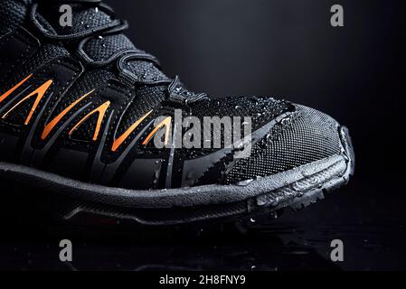 Black male boots for hiking on dark background. Waterproof shoes with water drops, close up Stock Photo
