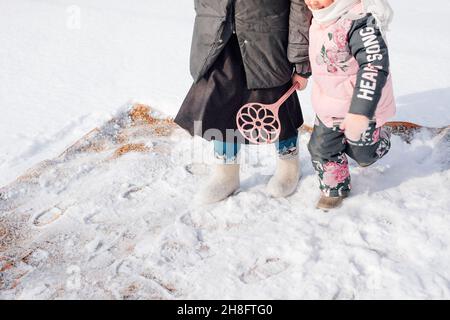 Russian tradition of carpet cleaning. Close-up of woman and child with carpet beater in their hands engaged in ecological carpet cleaning with fresh Stock Photo