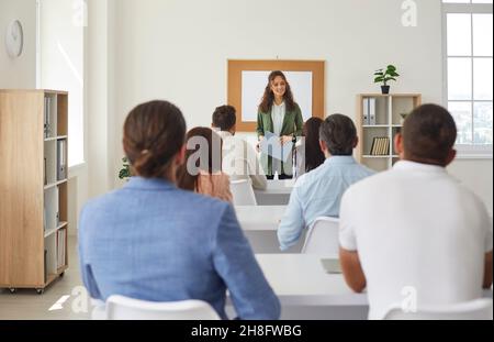 Female teacher teaches new business knowledge to adult students in training room. Stock Photo