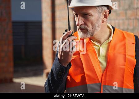 Focused construction expert having a conversation on the radio Stock Photo