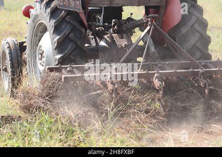 Tractor plowing the field with the help of a plow Stock Photo