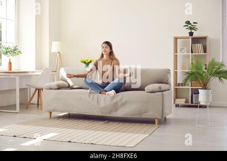 Calm woman sit on couch meditate at home Stock Photo