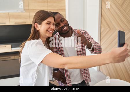 Joyous mixed-race couple posing for smartphone camera Stock Photo