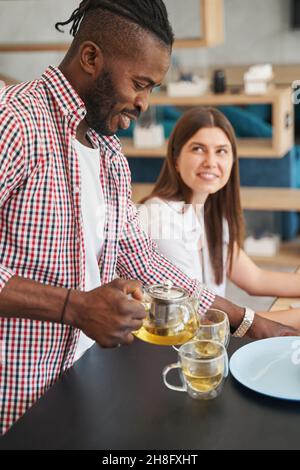 Smiling happy guy making chamomile tea for two Stock Photo