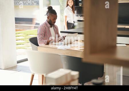 Woman watching man typing on notebook computer Stock Photo