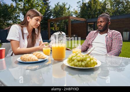 Female with cellphone and thoughtful guy seated at breakfast Stock Photo