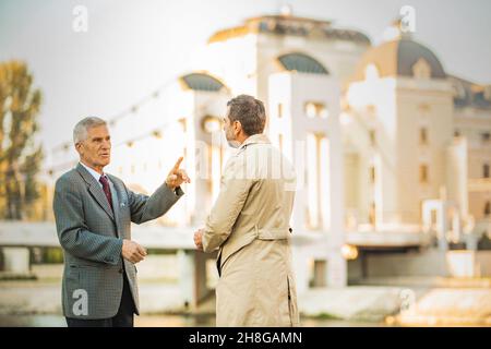 Two amazing senior businessmen are talking about the company by the river, close up Stock Photo