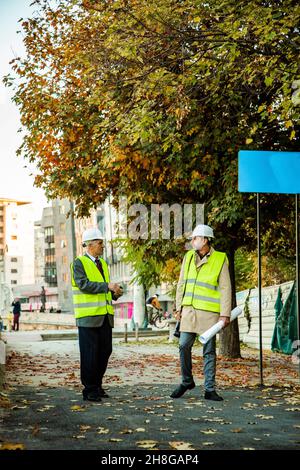 Two construction workers are walking together while talking to each other about the plans Stock Photo