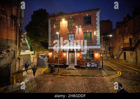 Manchester city centre cobbled street Wakefield St, with The Salisbury pub and a walkway to Oxford Road Railway Station Stock Photo