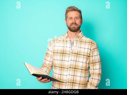 Young hipster man reading a book isolated over green background. Stock Photo