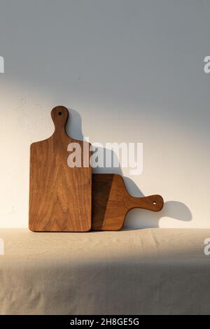 Two handmade wooden cutting boards are placed on the table against the wall. Stock Photo