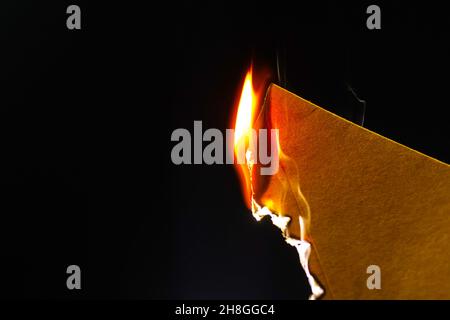 Burning piece of crumpled paper on black background photo Stock Photo