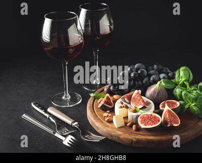 Gourmet wine and cheese appetizer set with camembert and figs. Dark toned image, copy space. Still life Stock Photo