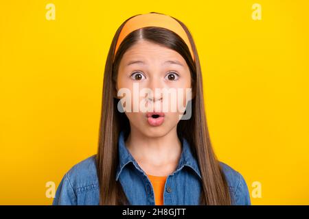 Photo of impressed shocked preteen girl dressed jeans shirt vintage headband big eyes isolated yellow color background Stock Photo