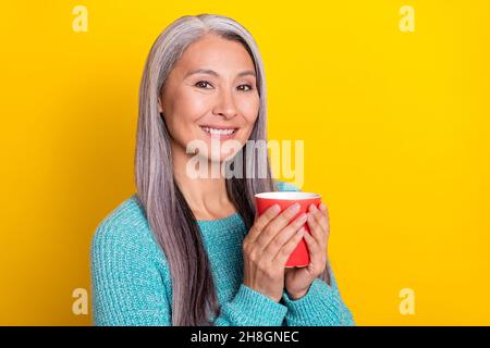 Portrait of attractive cheery grey-haired woman drinking tea copy space isolated over bright yellow color background Stock Photo