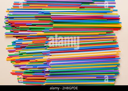 many multi-colored plastic tubes for cocktail on Colored background, top view. Stock Photo