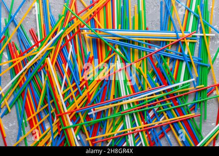 many multi-colored plastic tubes for cocktail on Colored background, top view. Stock Photo
