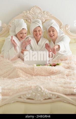 Young women in bathrobes at home with laptop Stock Photo