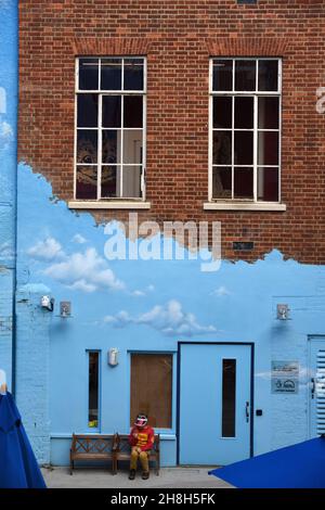 Boy Sitting on Bench in front of Blue Facade, Blue Wall & Blue Door in The Story Museum Oxford England Stock Photo