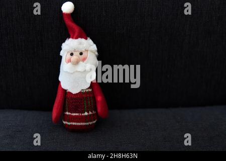 decorative miniature santa claus isolated on black background at night. Christmas ornament and postcard. Christmas, winter, new year concept. Flat lay Stock Photo
