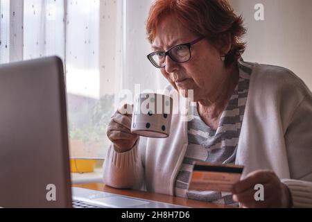 Senior woman using laptop and online shopping by credit card from home. Old people and internet Stock Photo