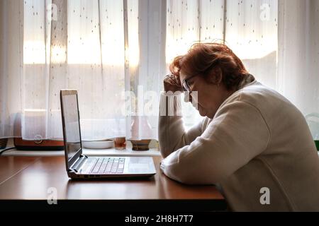 Worried senior woman browsing bad news at internet. Old people reading online news Stock Photo