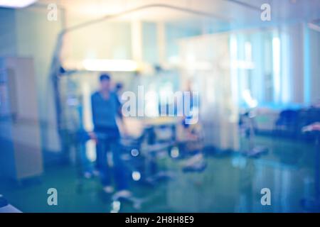 Male workers in the blue uniform next to the patient bed in the emergency room, unfocused background. Stock Photo