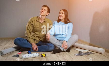 Couple enjoys room renovation sitting on parquet floor Stock Photo