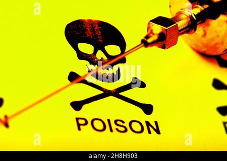 Old styled needle of medical syringe on the background of skull and crossbones - sign of toxicity. Stock Photo
