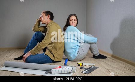 Young couple sits in dark room after quarrel over renovations Stock Photo