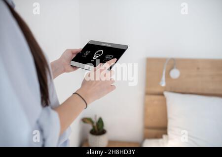 Woman turning on light using a tablet Stock Photo