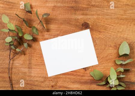 A blank paper on a wooden table with eucalyptus branches and leaves Stock Photo