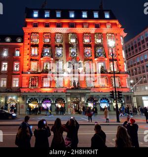 London, Greater London, England, November 28 2021: Tourists taking photos of Fortnum and Masons shop with its festive facade at night. Stock Photo