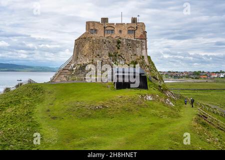 East elevation of Lindisfarne Castle with Lindisfarne Village in distance on Holy Island on the Northumberland Coast of England, UK Stock Photo