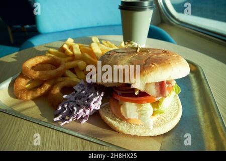 chicken and bacon burger onion rings coleslaw and fries meal on a ferry crossing the irish sea liverpool, merseyside, uk Stock Photo
