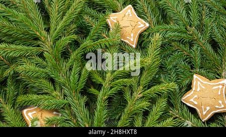 Background of Christmas tree branches with cookies in the shape of stars Stock Photo