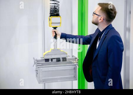 Worker engineer uses intelligent industrial manipulator lift easy with gripper in factory. Stock Photo