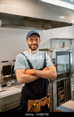 Joyful male worker standing in cafe kitchen Stock Photo