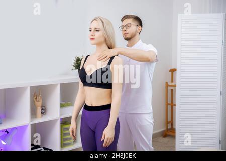 Doctor performs sports massage therapy for young woman athlete after workout. Stock Photo
