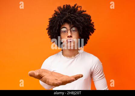 Funny upset african american guy pouting lips, holding something invisible Stock Photo