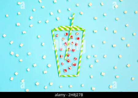 Cup of Christmas hot drinks made from green drinking straws on winter blue background. Tea, hot chocolate with Candy cane. Creative winter minimal concept. Unique flat lay. Stock Photo